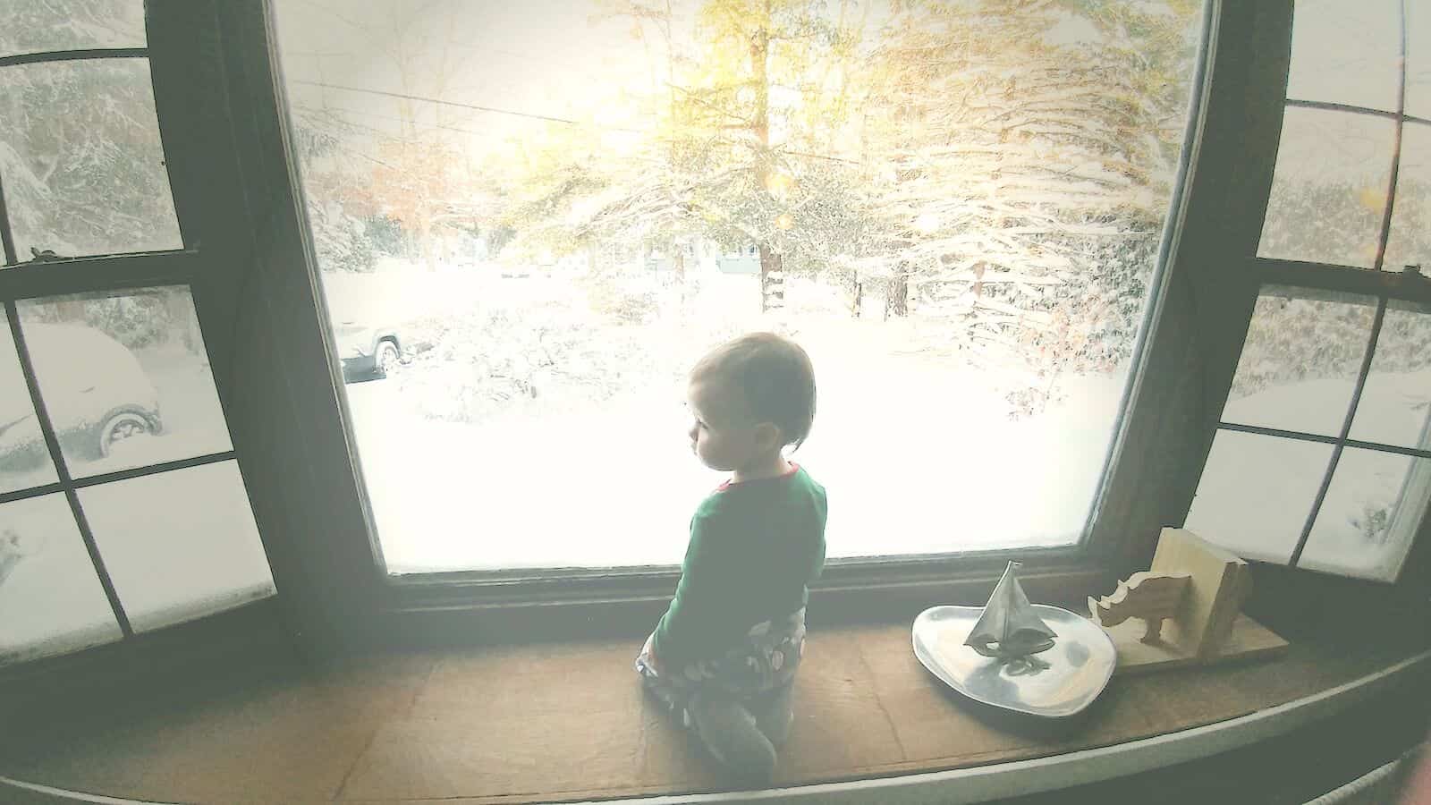 Toddler girl looks out window.