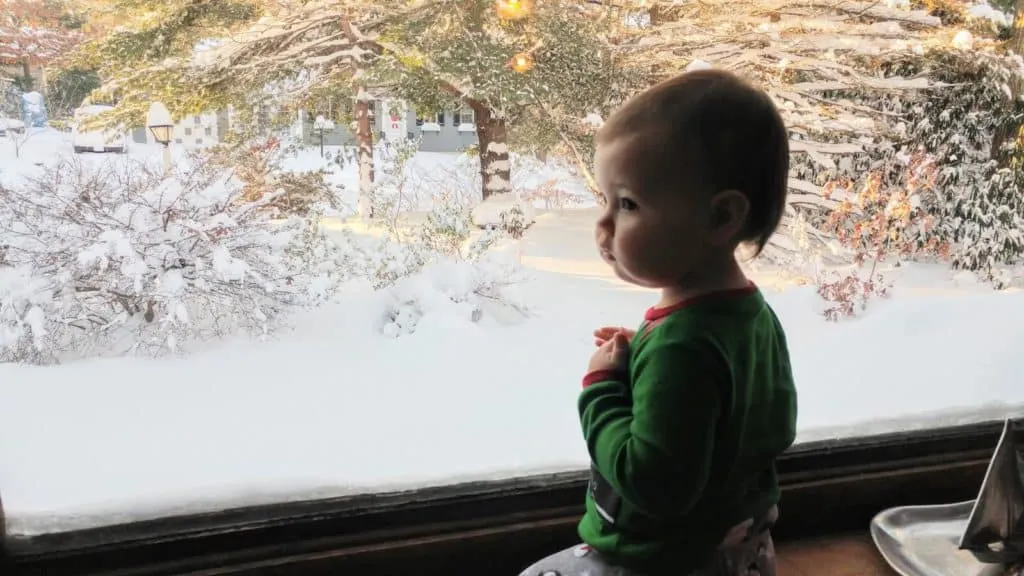 Baby girl sits in window.