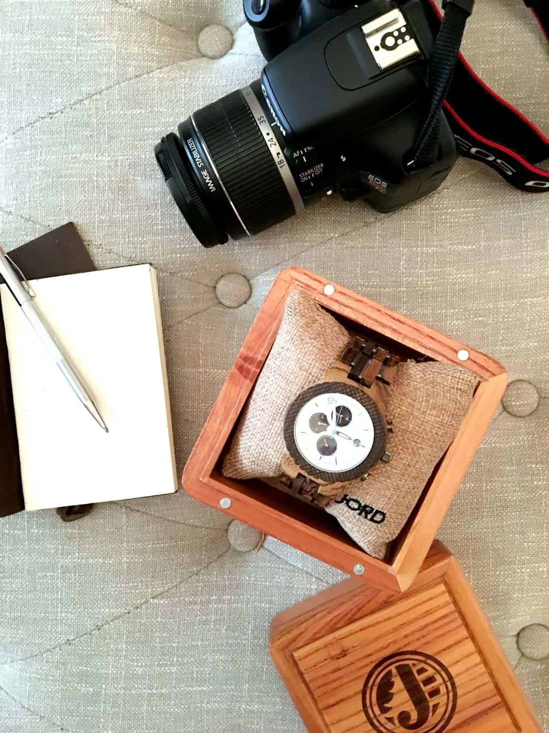 Jord watch next to camera and notebooks.