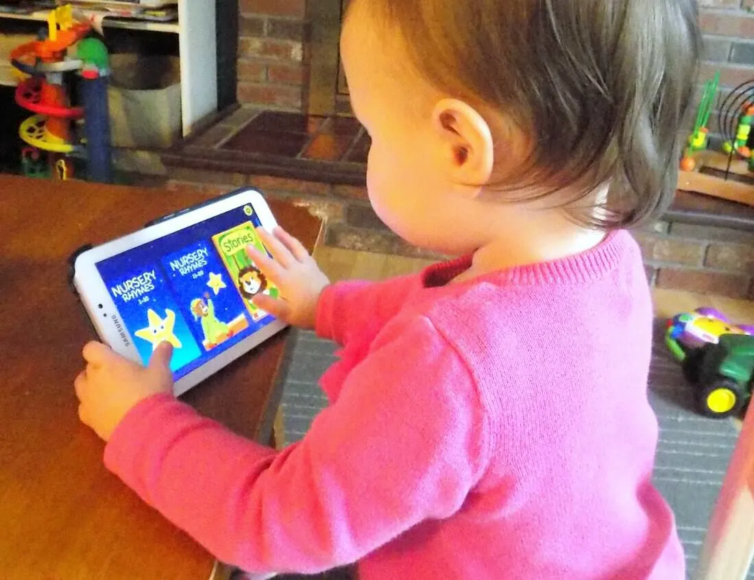 Toddler girl plays with tablet.