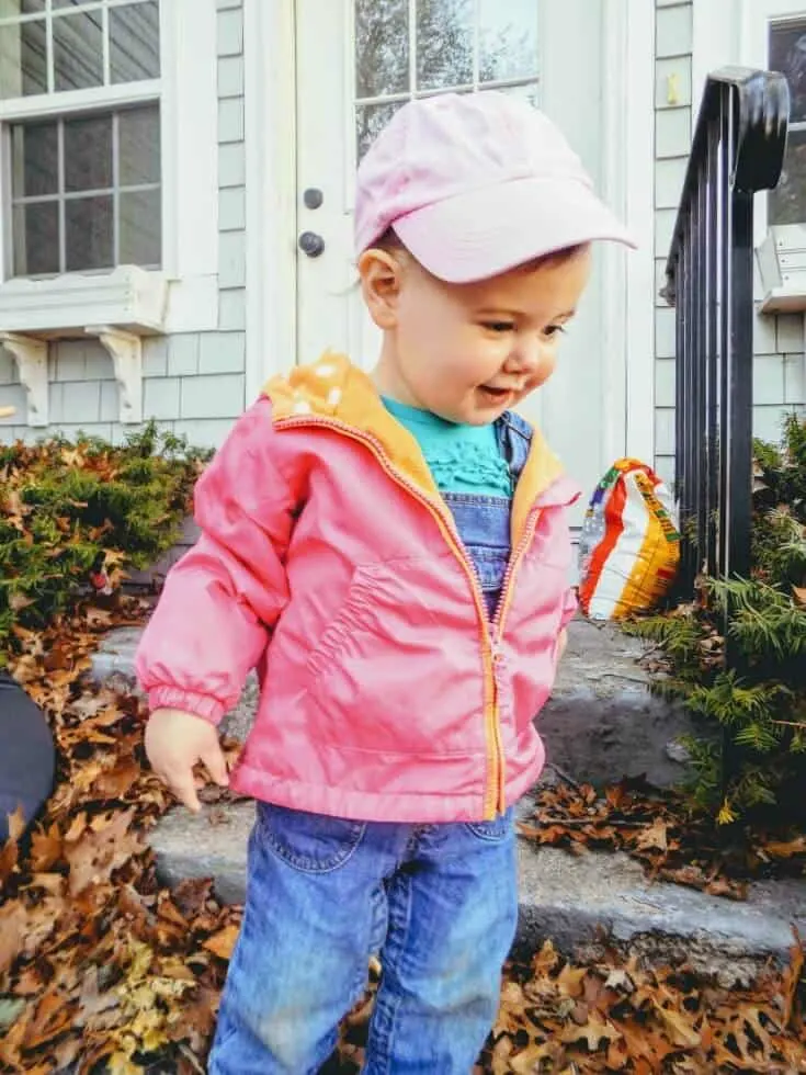 Baby girl plays outside in front of doorsteps.