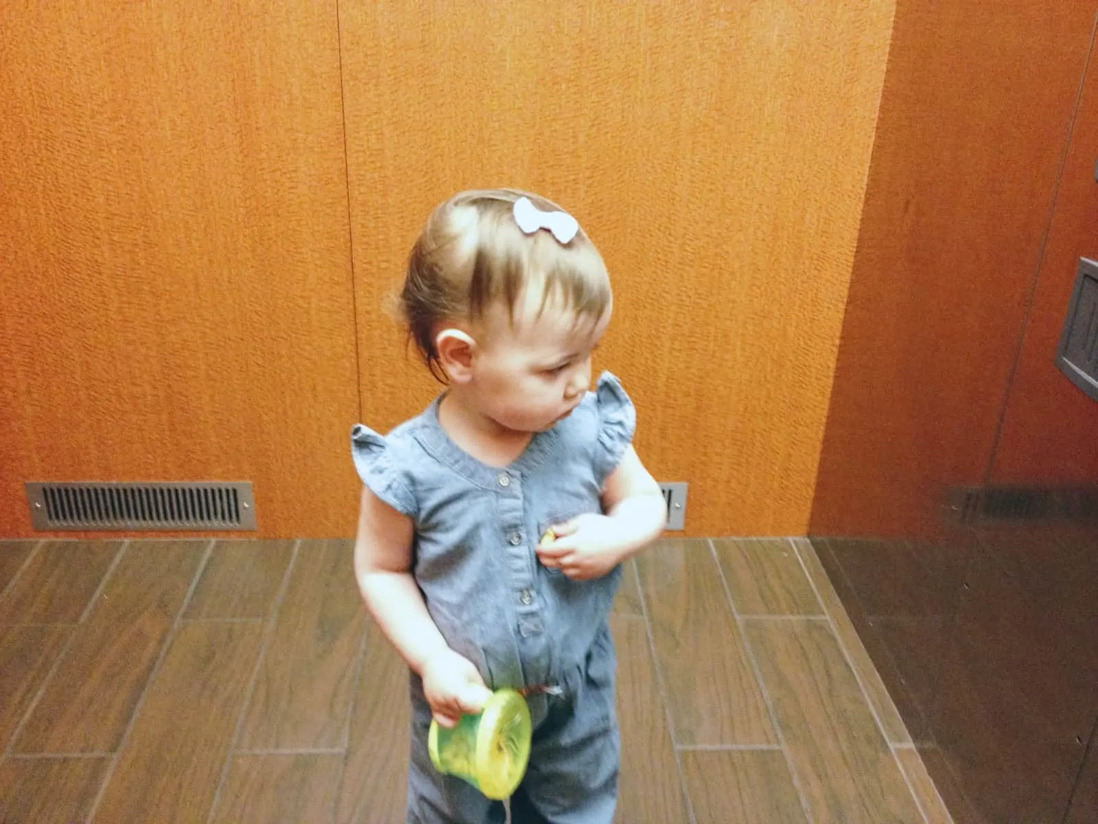 Toddler girl holds snack cup.