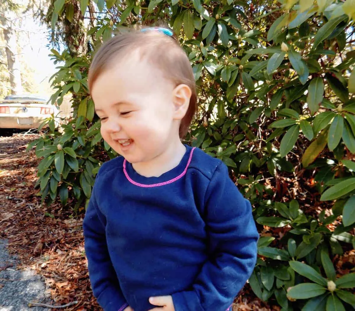 Toddler girl plays outside.