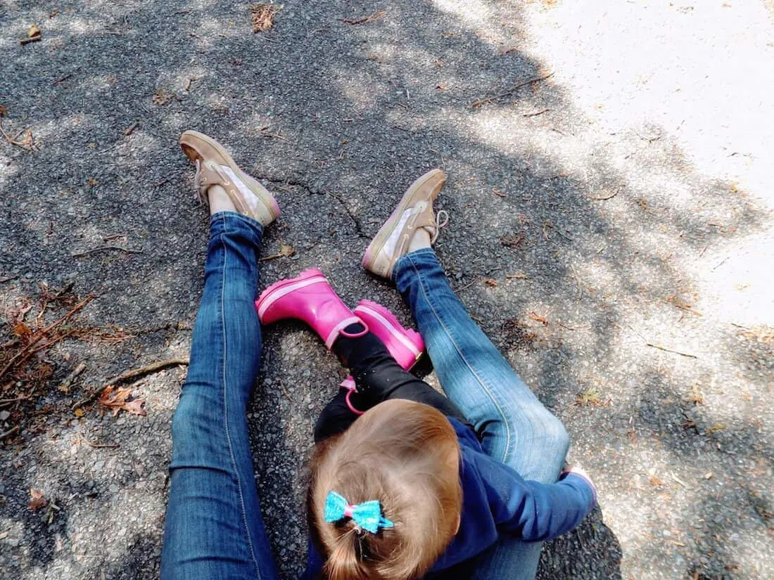 Mom helps toddler girl stay safe from ticks while playing outside.