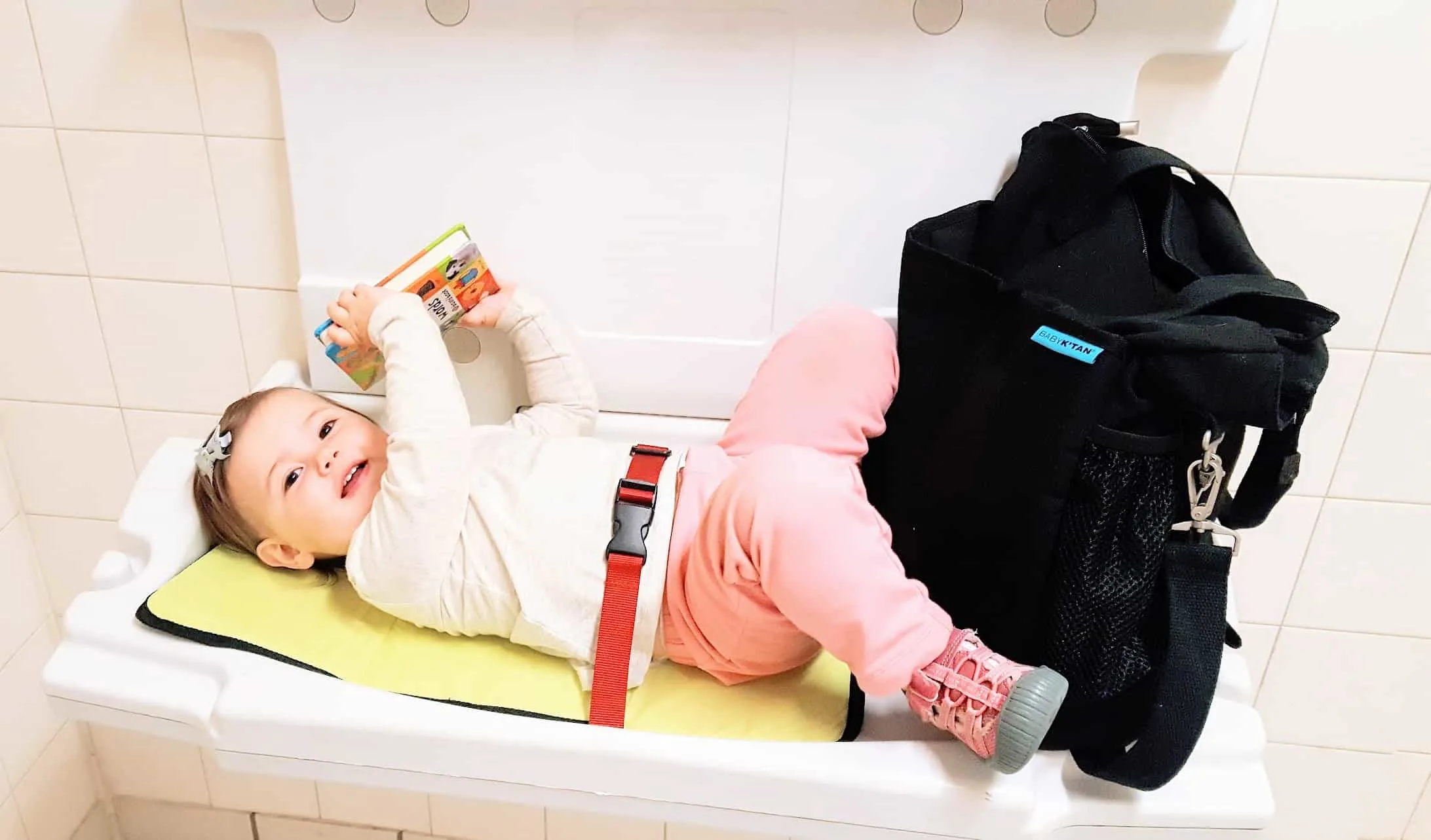 Little girl strapped into changing table in restroom.