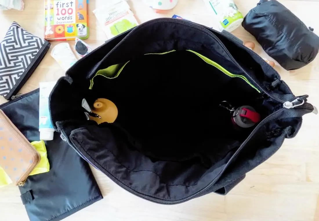 Large diaper bag sits opened next to baby items.