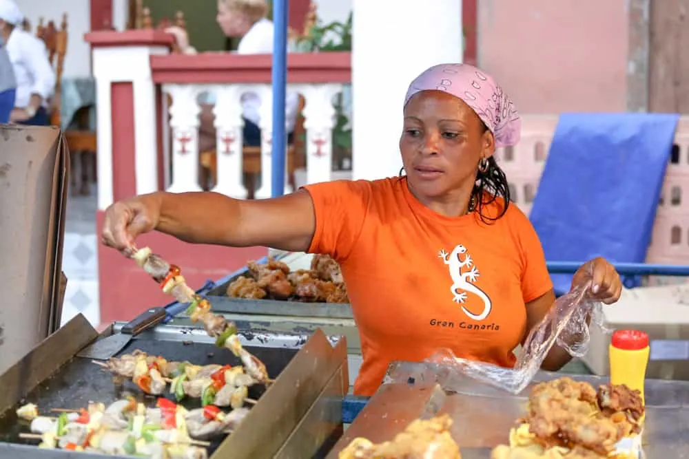 Woman cooks kabobs on outdoor grill.