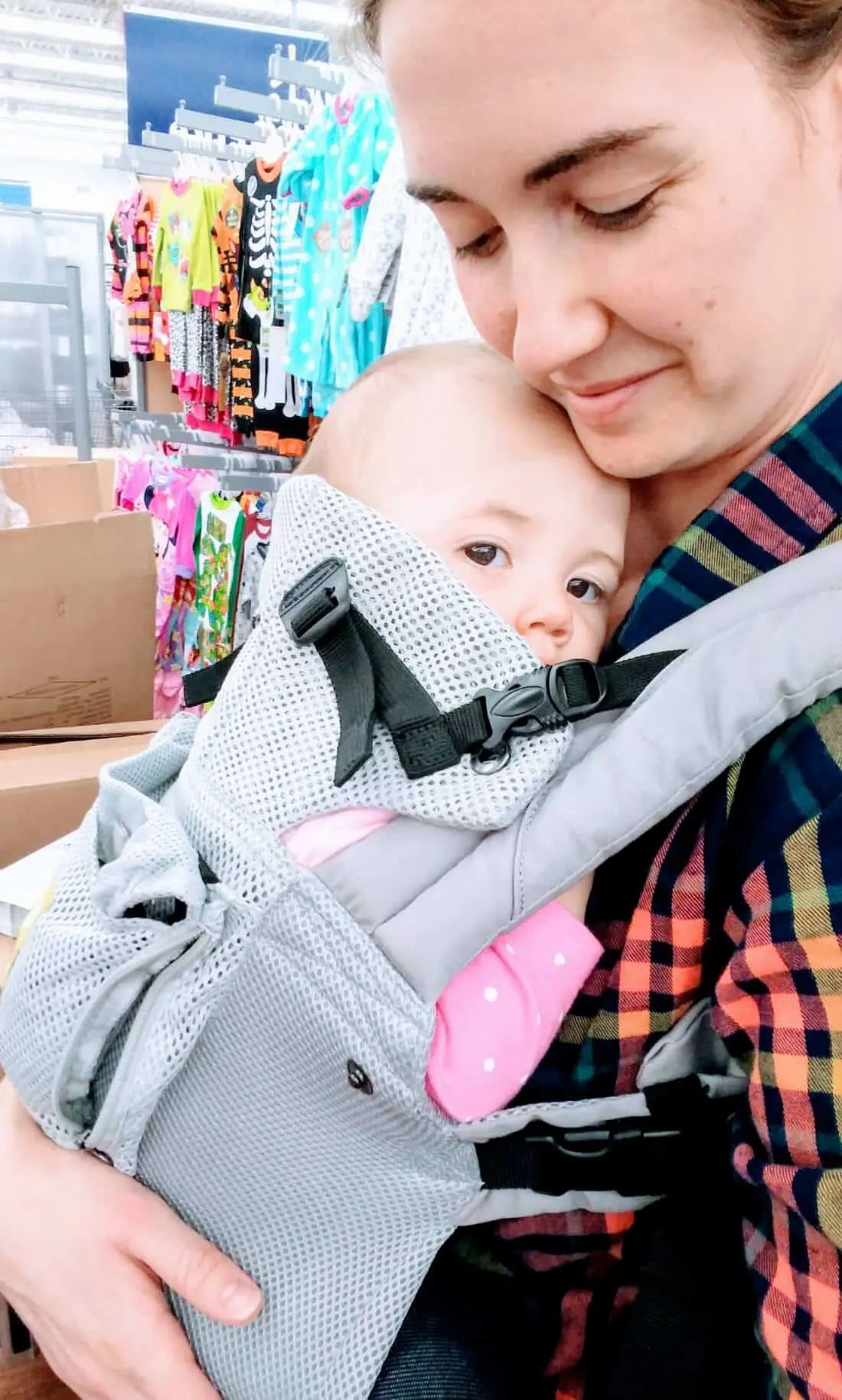 Mom wears baby at store using baby carrier.