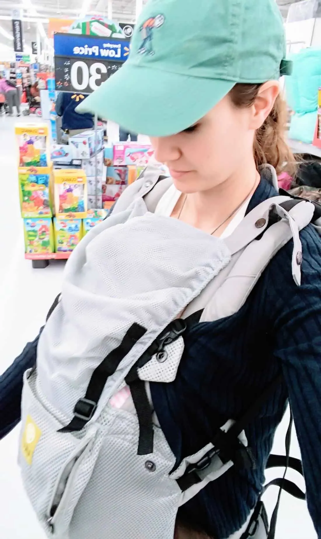 Mom wears baby in carrier at store.