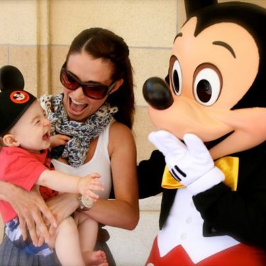 Mom introduces little girl to Mickey Mouse at Disneyland.