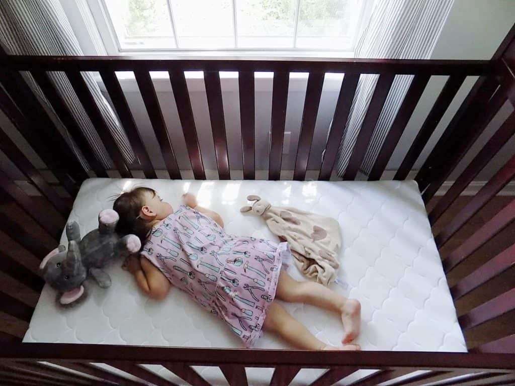 Toddler girl sleeps in crib.