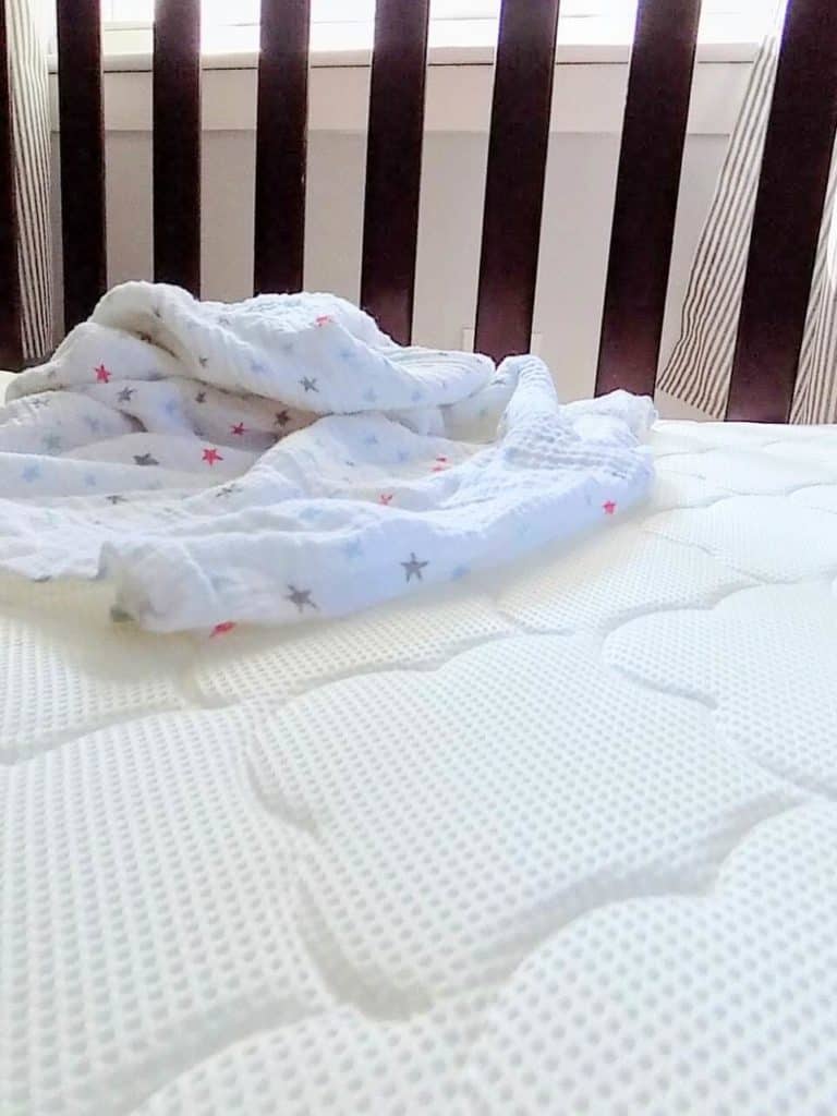 Baby blanket sits on top of Wovenaire crib mattress.