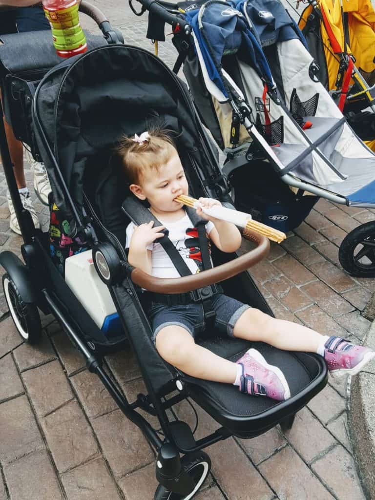 Little girl eats treat at Disney.