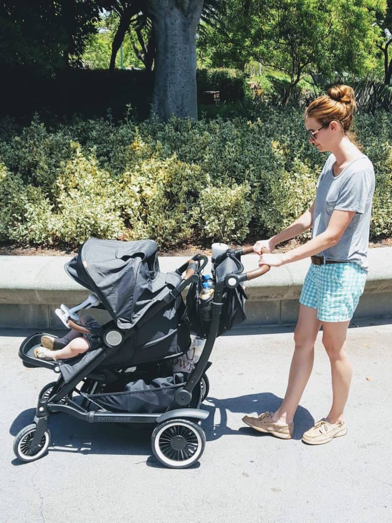 Mom pushes child in stroller down paved path.