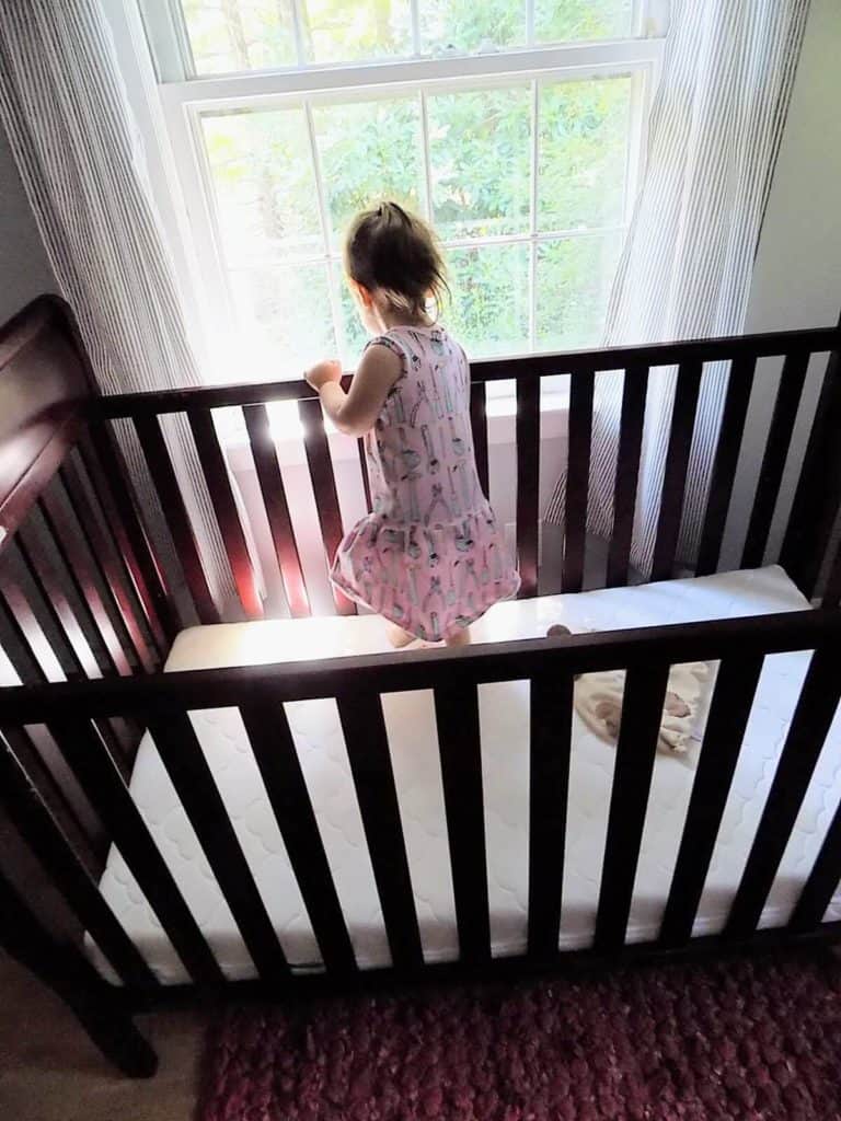 Toddler girl stands in crib.