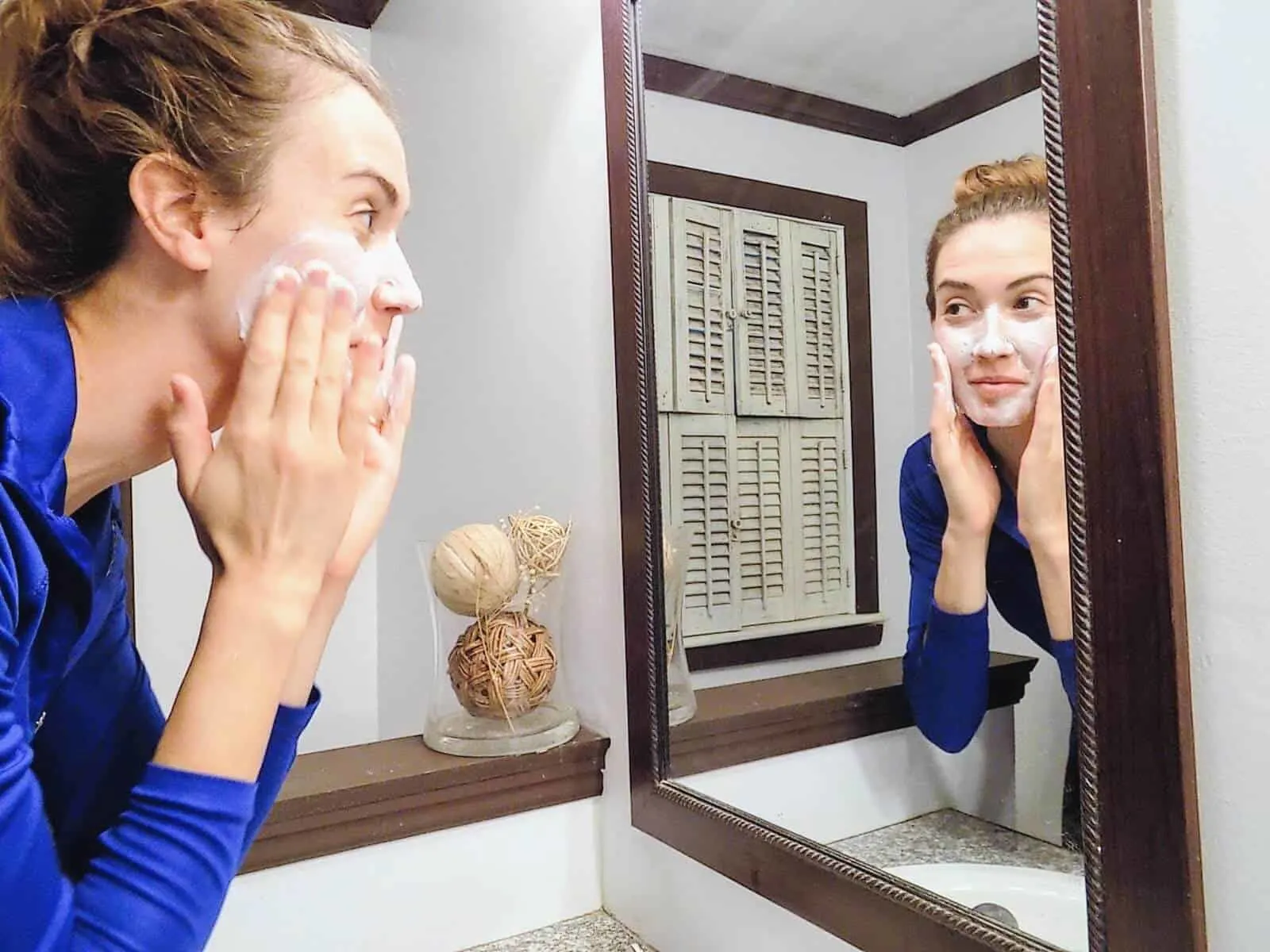 Woman washes face in mirror.