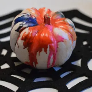 Painted pumpkin for Halloween on \"spider web\" place mat.