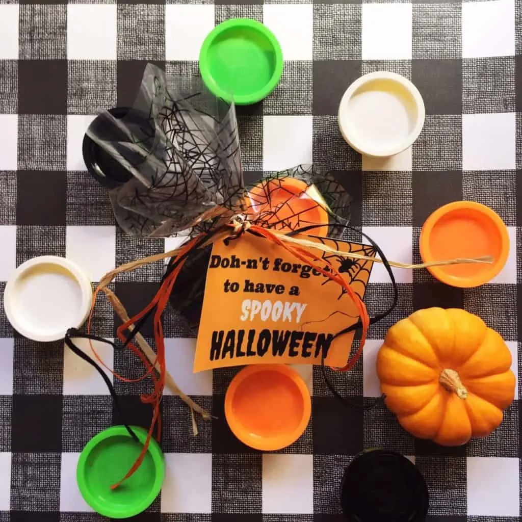 Halloween activity with play dough and pumpkins on checkered tablecloth.