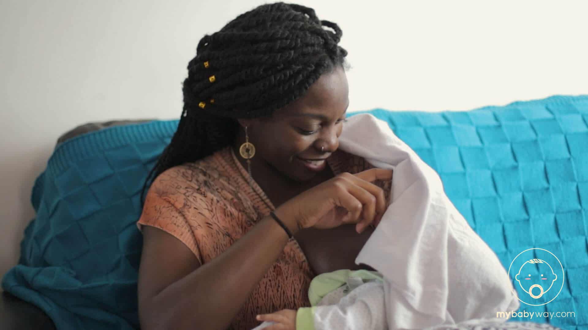 Mother nurses baby under nursing cover.