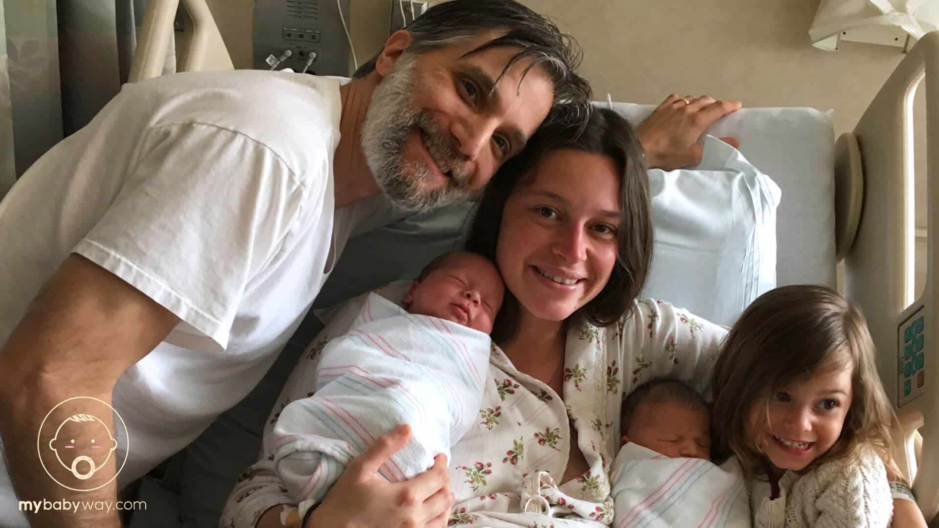 Couple poses with newborn twins at hospital.