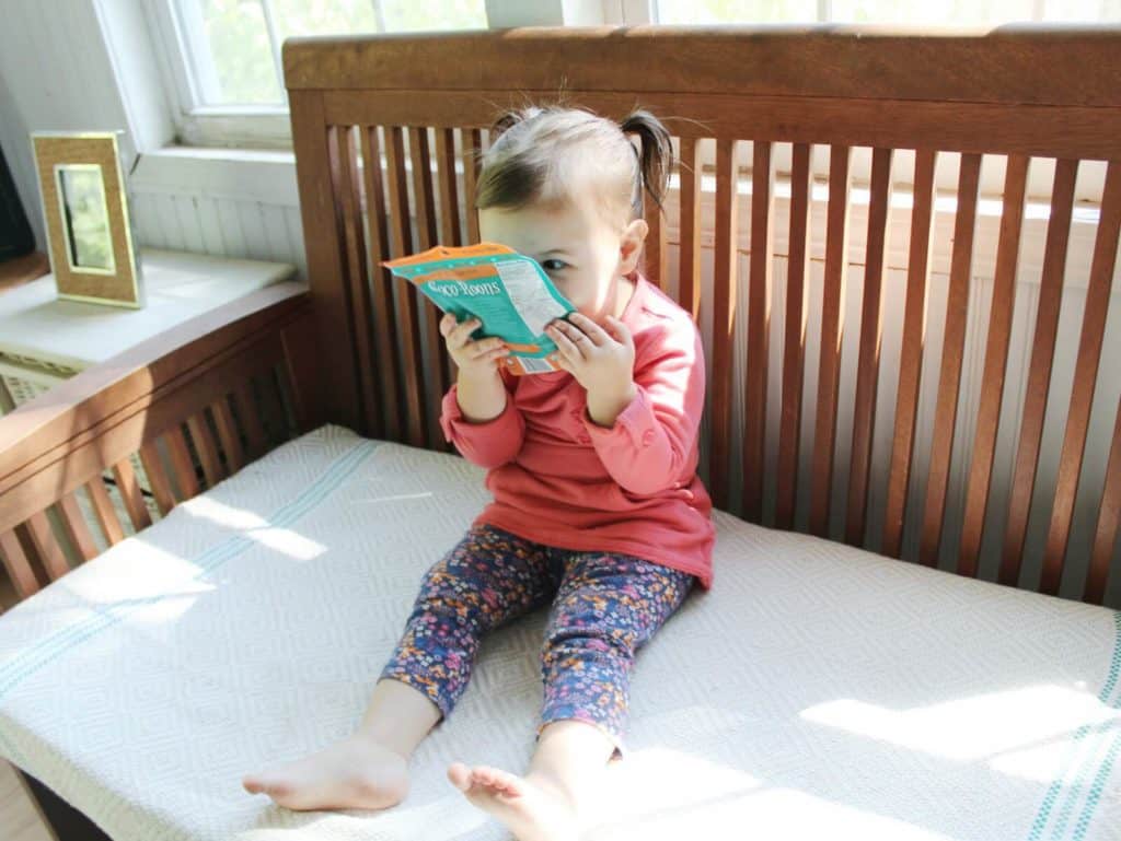 Toddler girl holds Coco-Roons bag close to face.