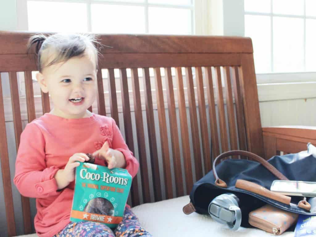 Child holds bag of cookies on indoor bench.