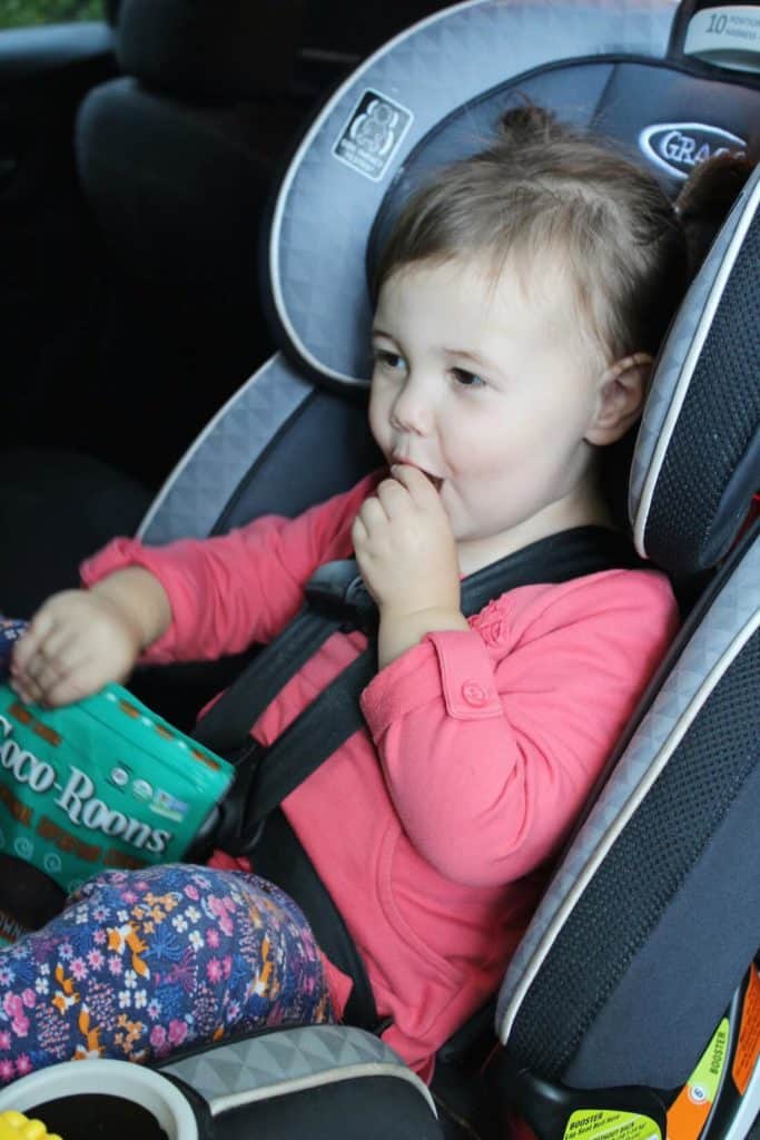 Little girl eats Coco-Roons in car seat.
