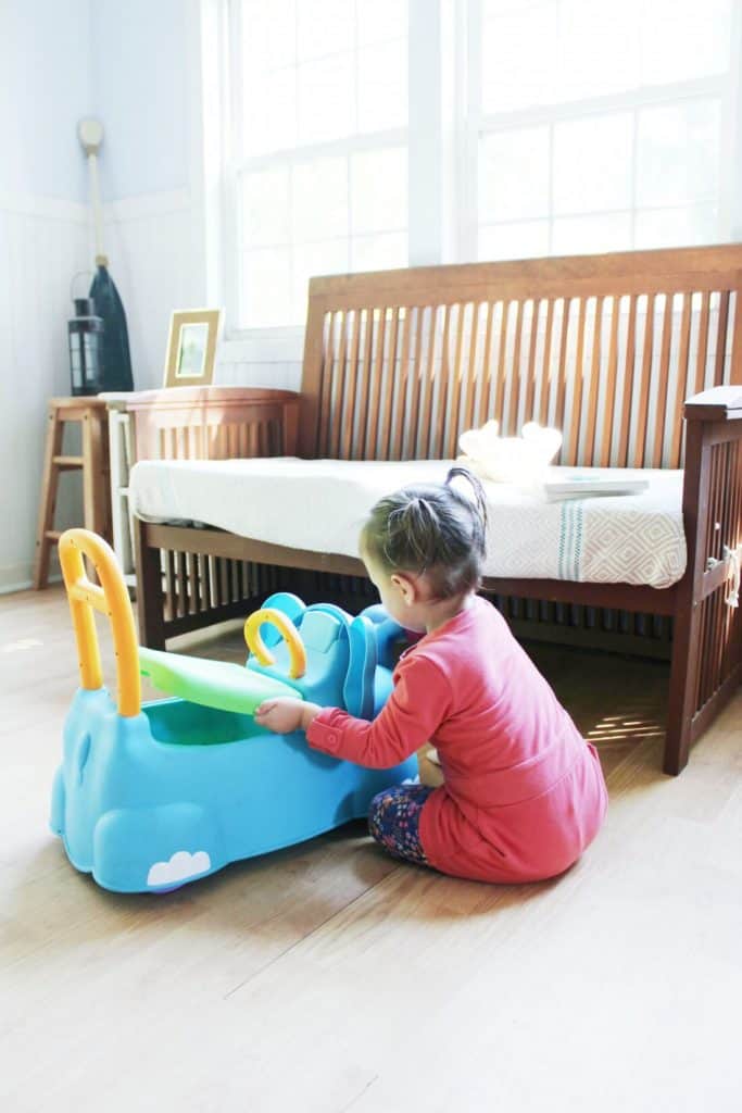 Little girl plays with push car.