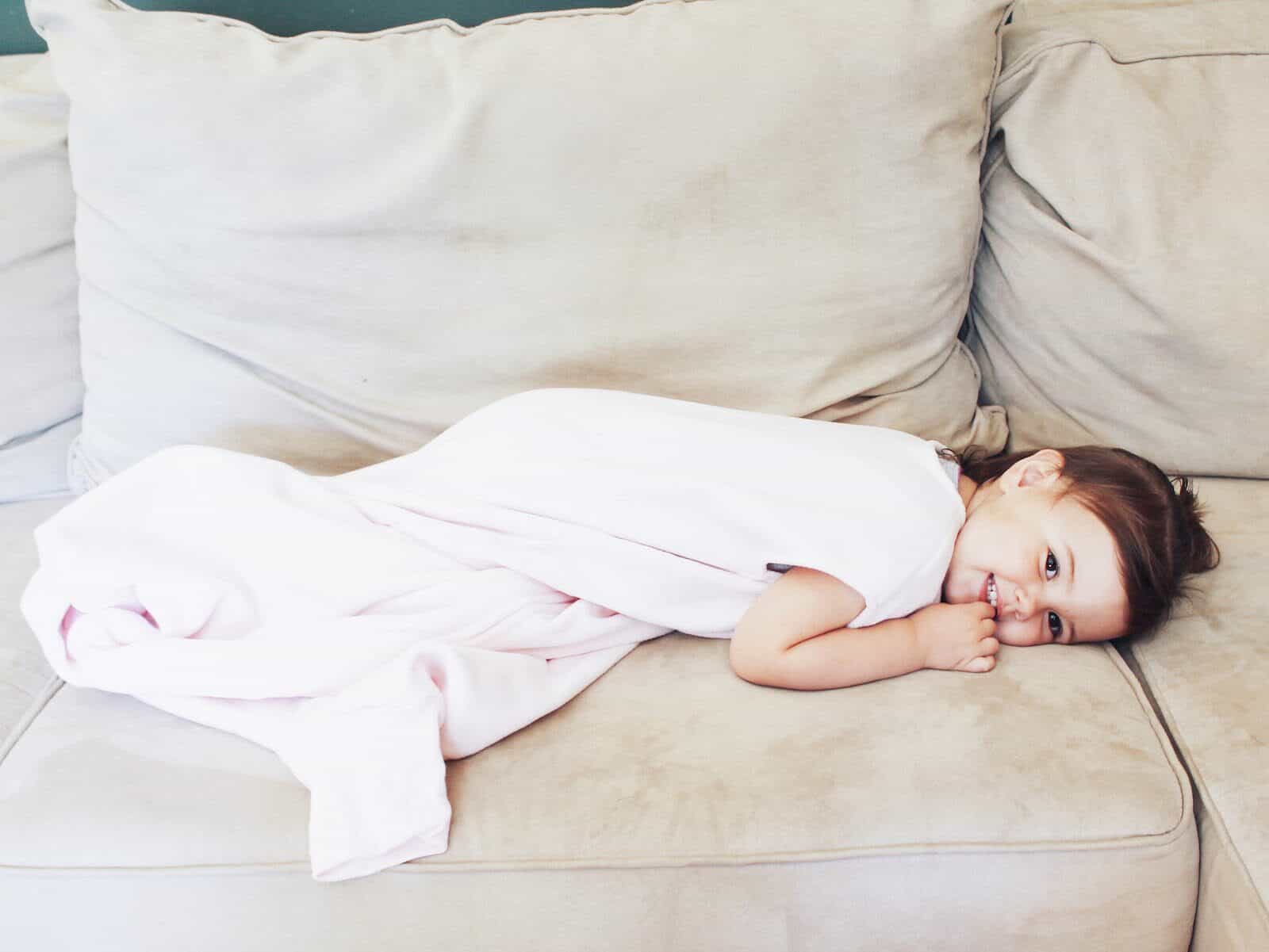 Toddler girl lays on couch.