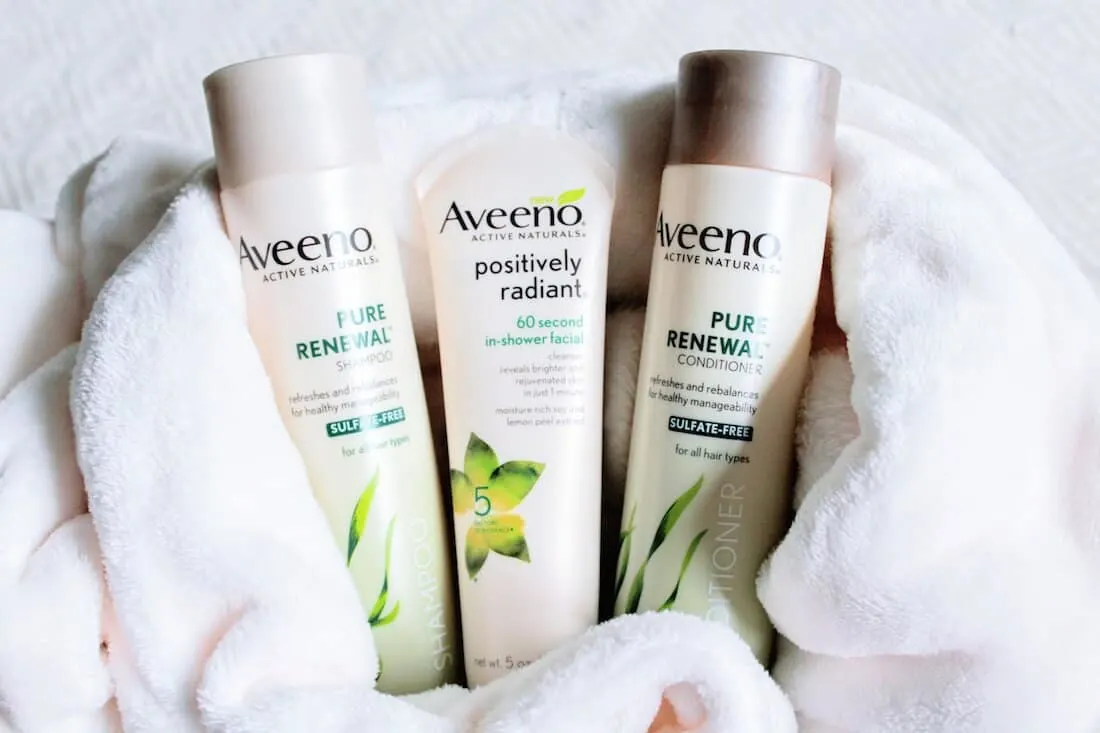 Aveeno skin care products on white towel.