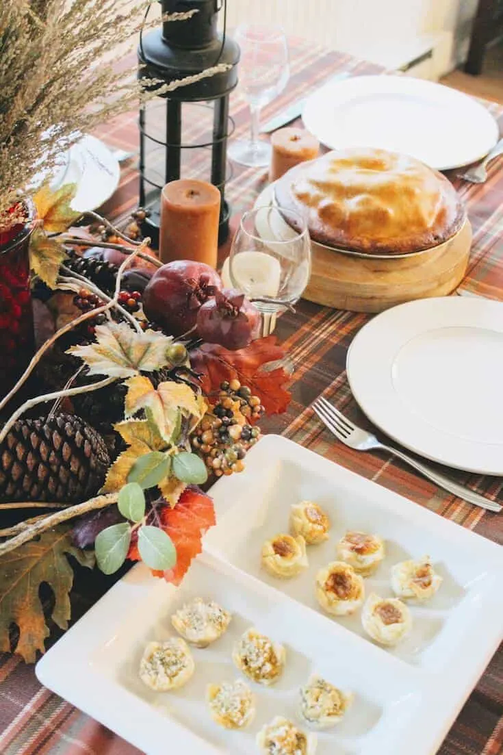 White plates on Thanksgiving table with food.