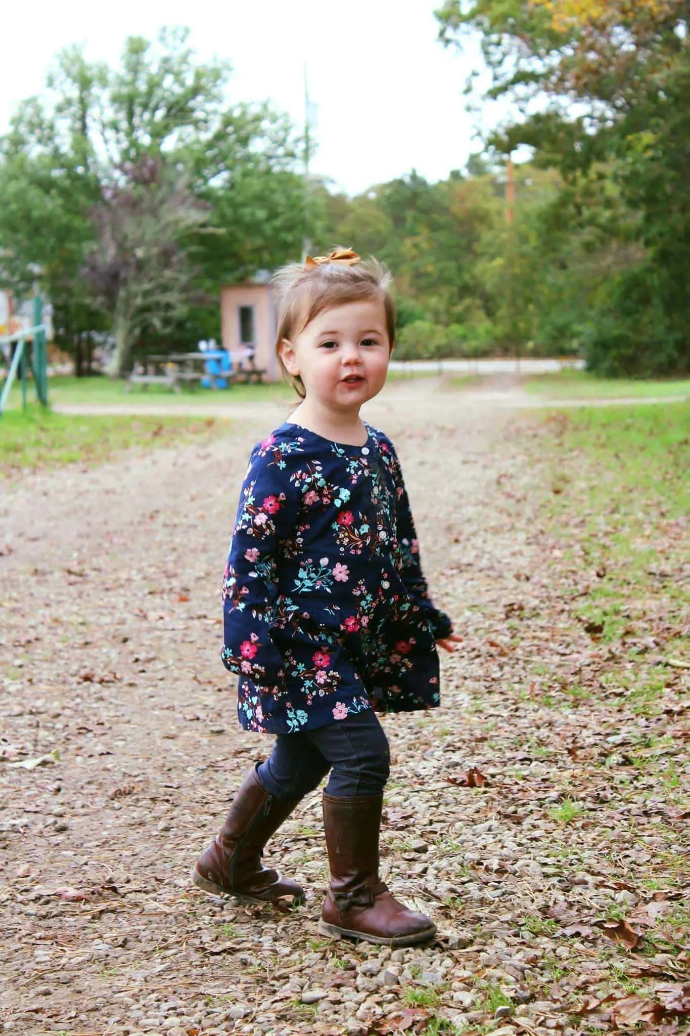 Little girl stands on pumpkin patch path.
