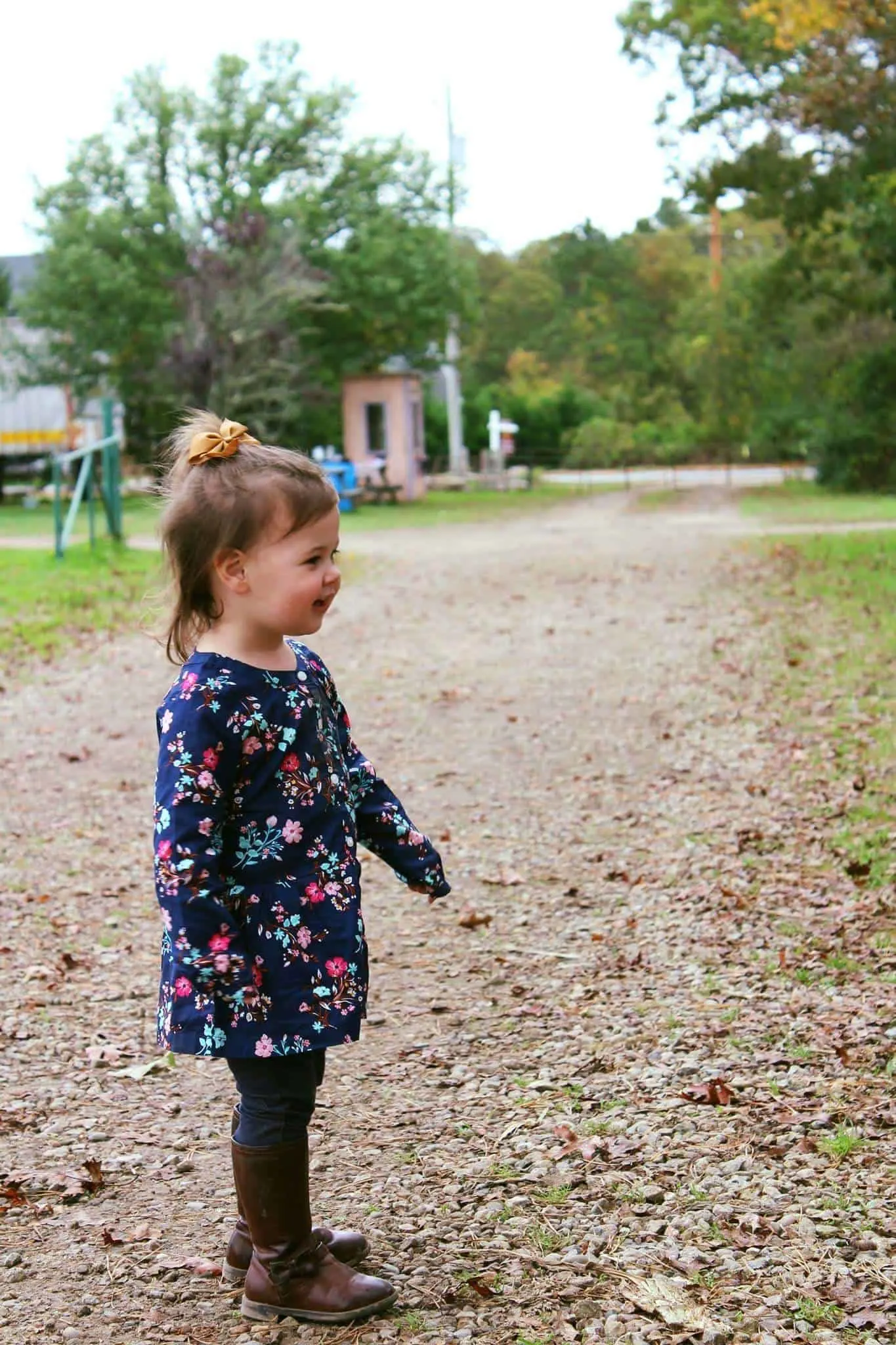 Little girl plays outside on dirt road.