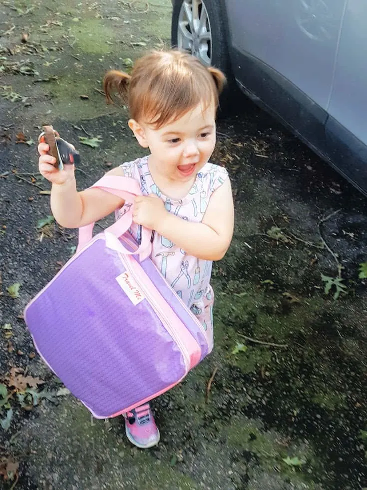 Toddler girl carries entertainment bag for travel.