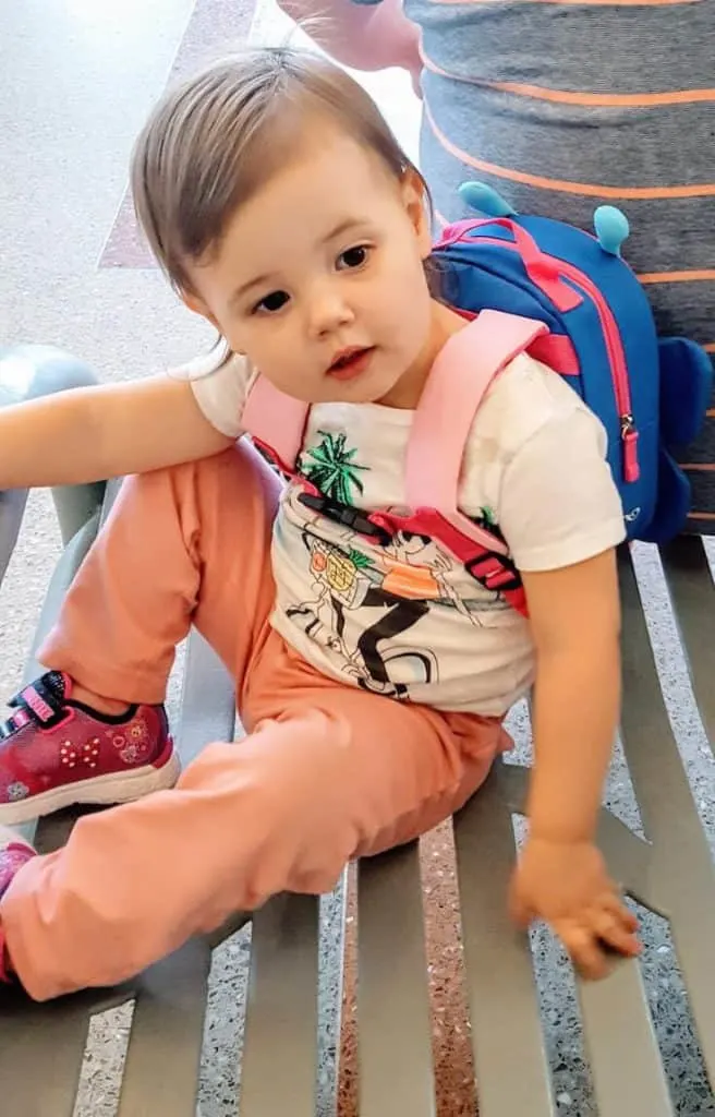 Toddler girl wears backpack for travel.