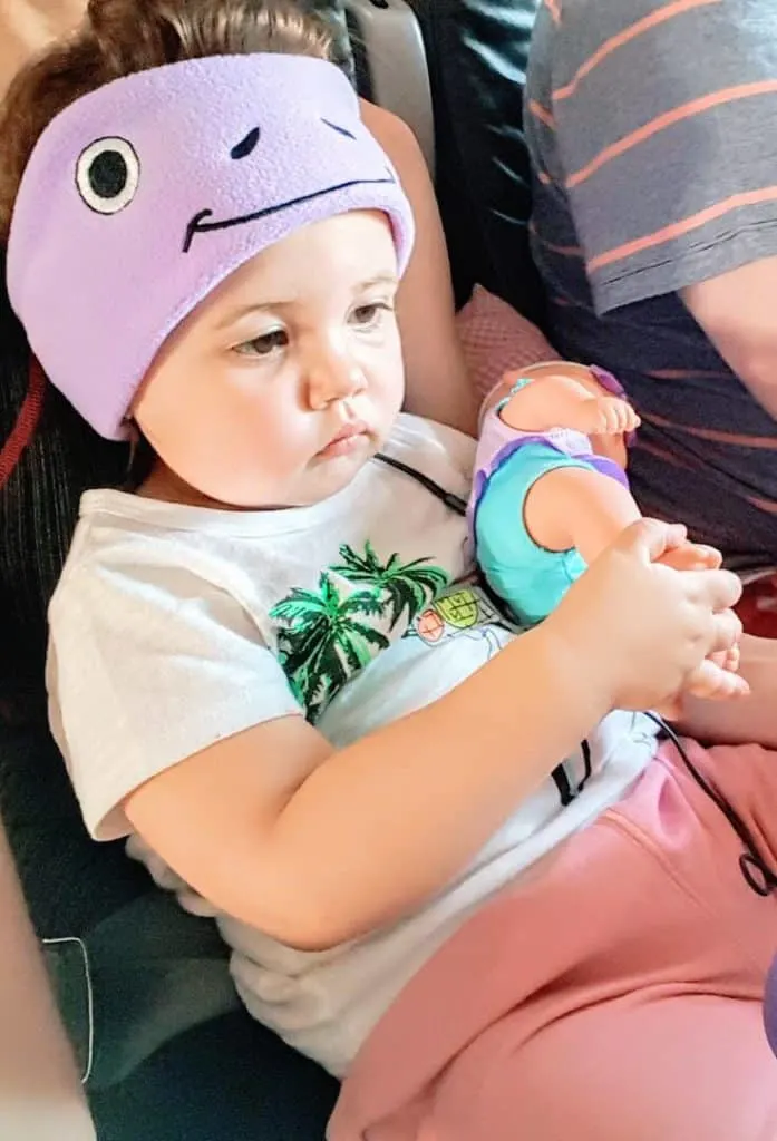 Toddler girl plays with doll on plane trip.