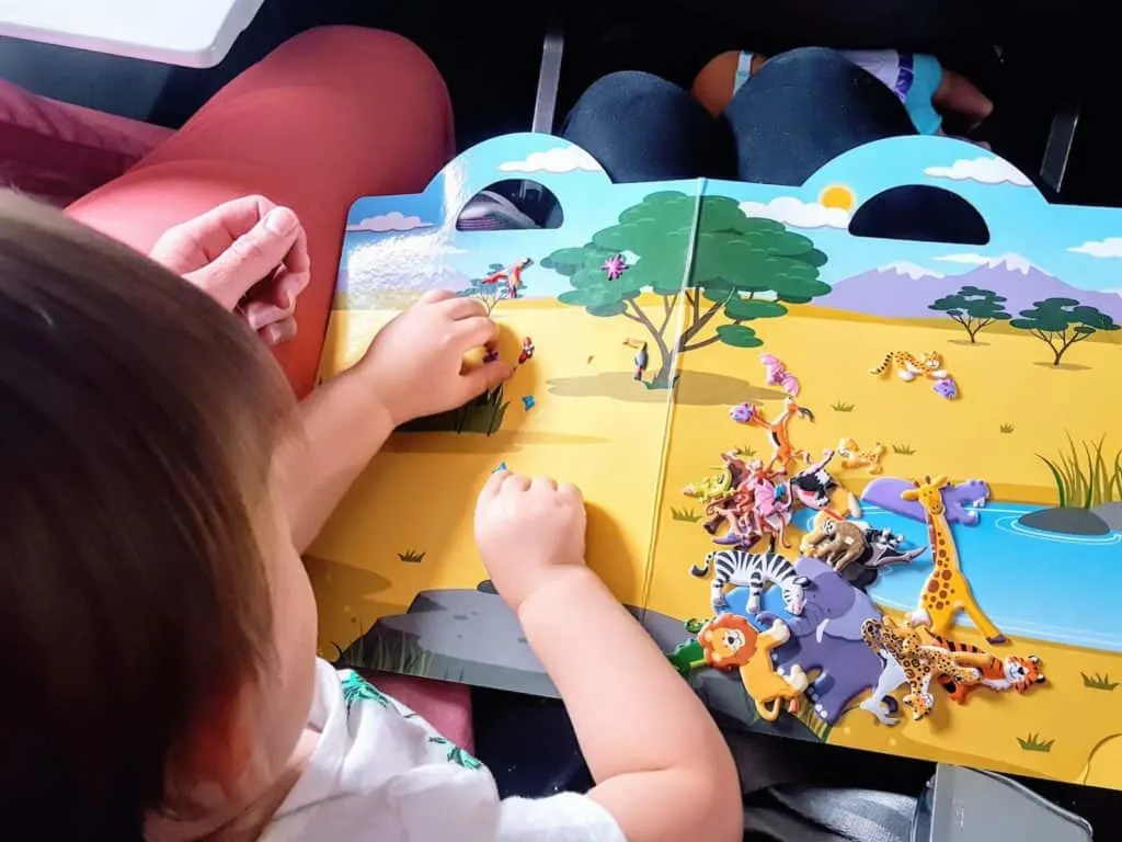 Toddler girl stays entertained on flight with book.