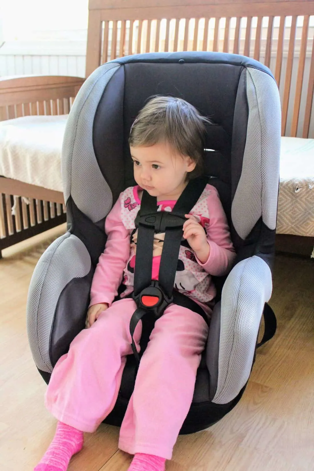 Toddler girl is strapped into carseat.