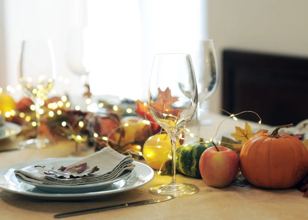 A dining table with pumpkin centerpieces in yellow, orange, and green.