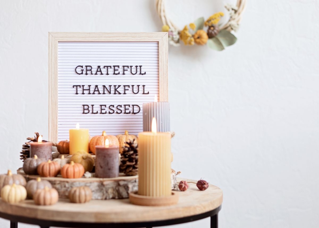 A decor stand with candles and a sign that says, "Grateful, Thankful. Blessed".