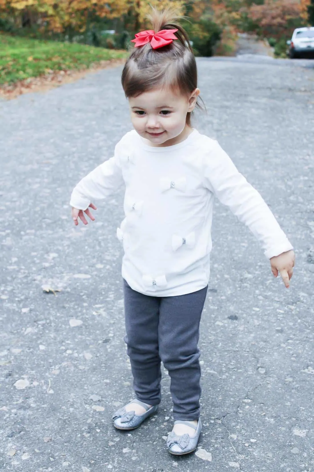 Toddler girl walks down street during holiday season.