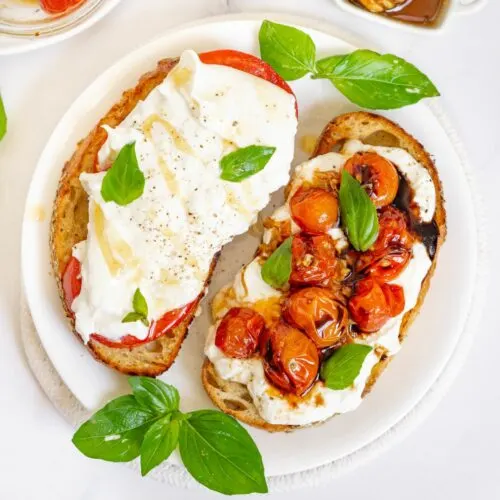Toast with burrata and blistered tomatoes and green garnish.
