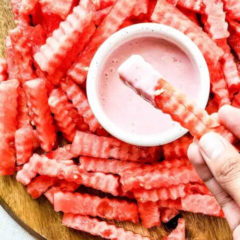 Watermelon fries on a serving platter with a bowl of strawberry yogurt dip.