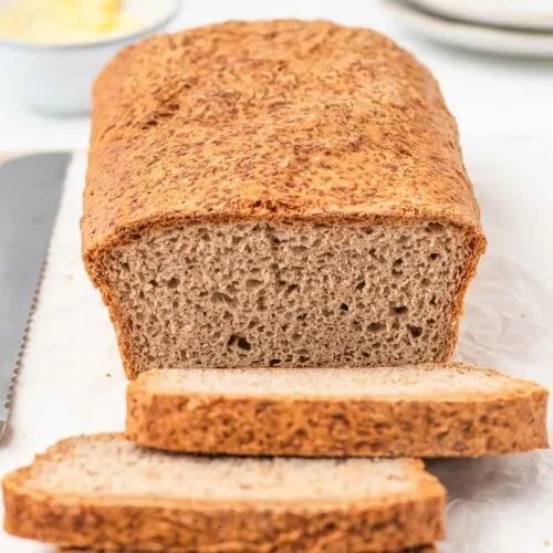 A loaf of homemade buckwheat bread with two slices cut off.
