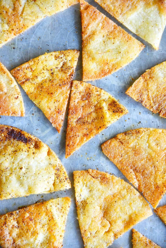 Homemade tortilla chips with chili seasoning on a sheet pan.