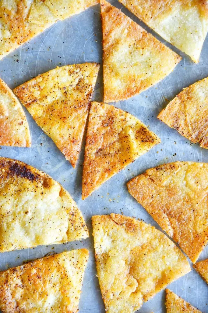 Homemade tortilla chips with chili seasoning on a sheet pan.