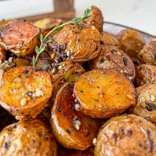 Za'atar seasoned roasted potatoes in a bowl with green garnish.