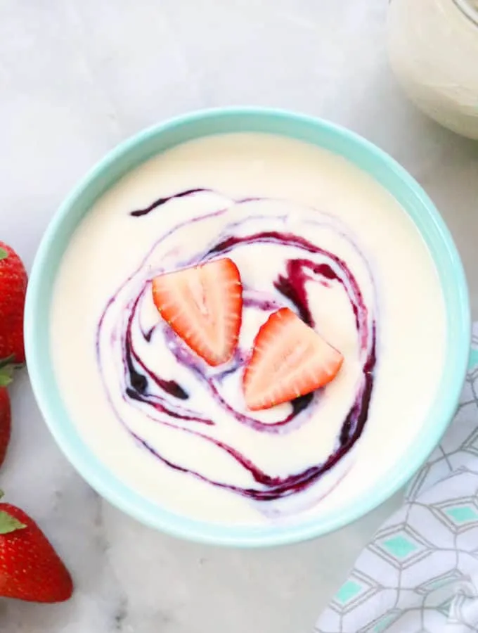 Homemade yogurt with strawberries in a blue bowl.