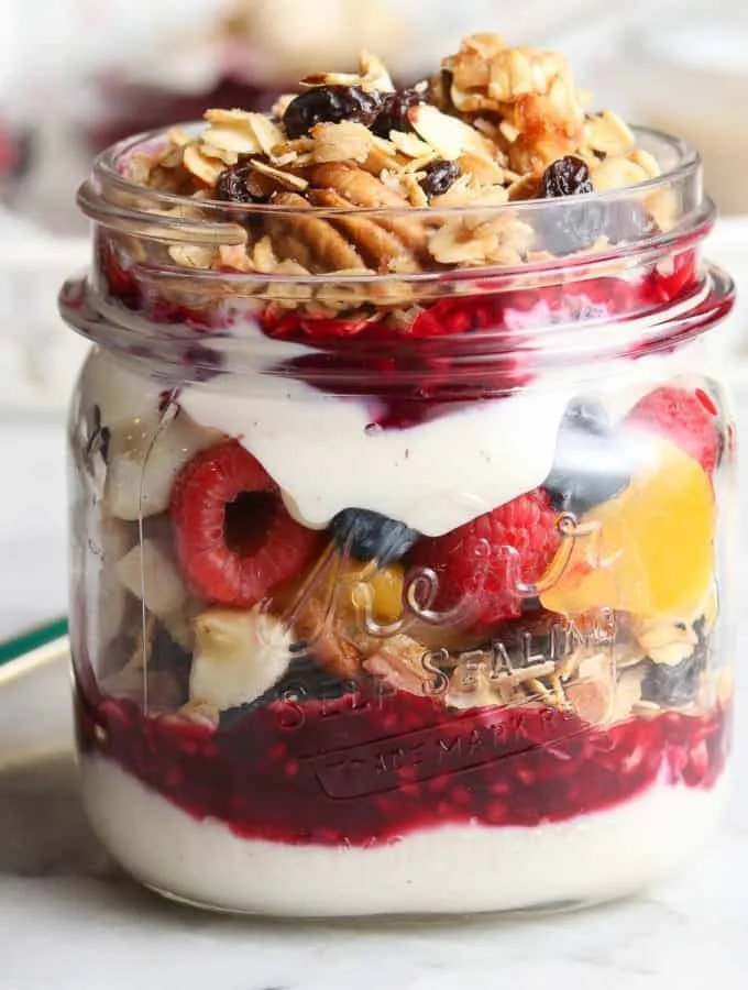A yogurt parfait with granola and berries in a glass jar.