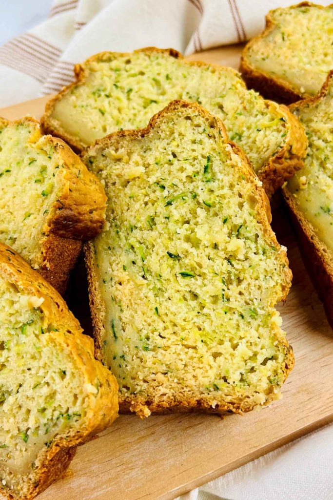Slices of homemade zucchini bread on a wooden cutting board.